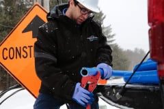 Contractor cutting a water line freeze protection system with cutting pliers at job site