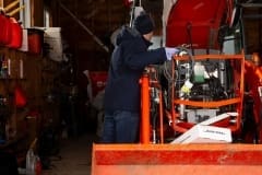 Contractor installing self-regulating low voltage heat trace system in orange tractor