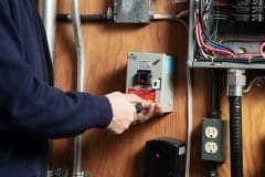 Contractor closing MilliAMP ELCI/GFCI on a indoor wall with other electrical appliances