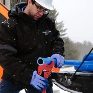 Contractor cutting a water line freeze protection system with cutting pliers at job site