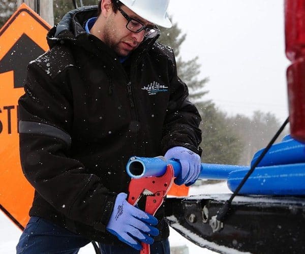 Contractor cutting a water line freeze protection system with cutting pliers at job site