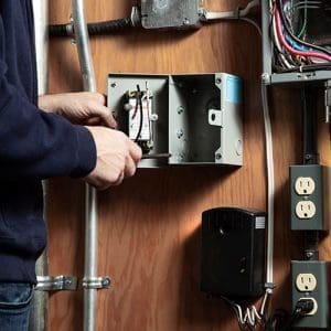 Contractor opening MilliAMP ELCI/GFCI on a indoor wall with other electrical appliances