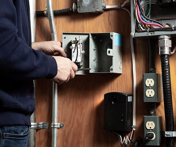 Contractor opening MilliAMP ELCI/GFCI on a indoor wall with other electrical appliances