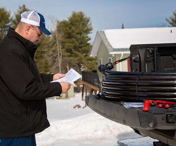 Heat-Line on Tailgate with Contractor reading self-regulating heat trace cable installation instructions