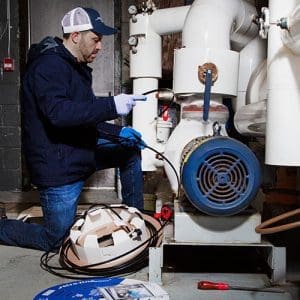 Contractor installing external self-regulating heat trace system on pipe indoors