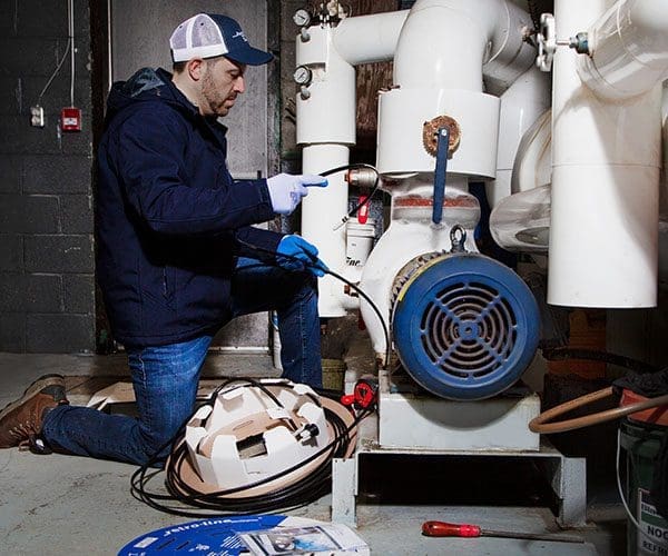 Contractor installing external self-regulating heat trace system on pipe indoors