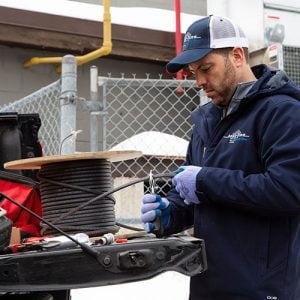 Contractor cutting self-regulating heat trace cable from reel on tailgate
