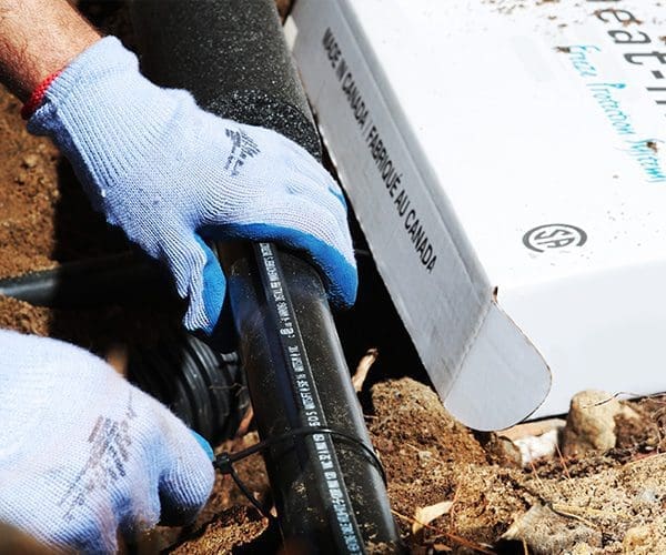 Contractor installing external self-regulating heat trace system to pipe outdoors