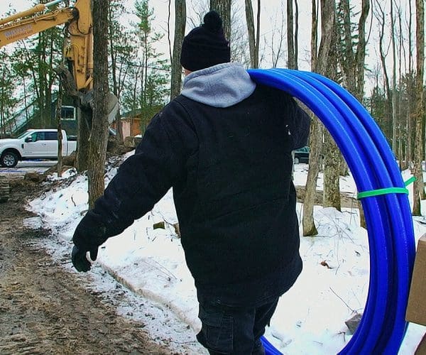 Contractor carrying water line freeze protection system over shoulder to job site